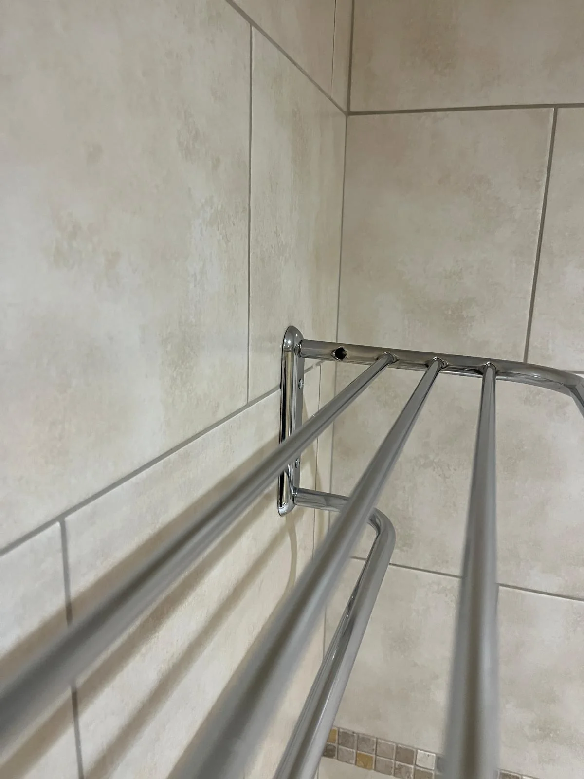 Close view of shower rail fittings secured to tiled wall