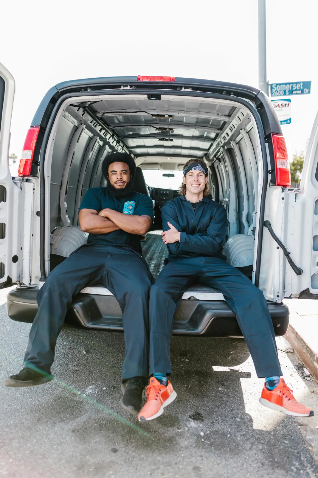 Two maintenance operatives seated at the rear of a work van