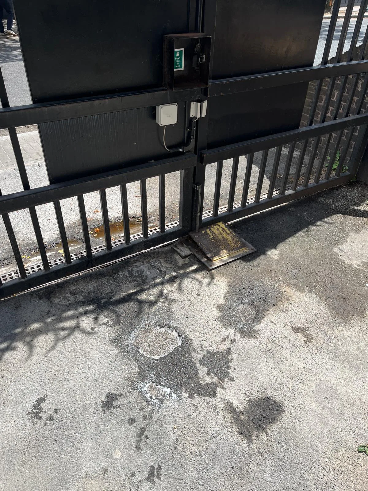 Damaged surface and potholes beside entrance gate before repairs